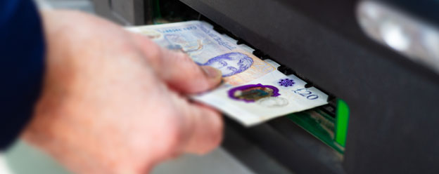 Customer withdrawing cash from an ATM and placing into their wallet.